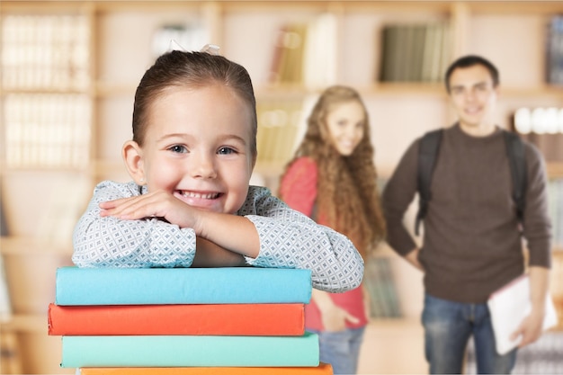 Weinig schoolmeisje die met boeken bij camera glimlachen