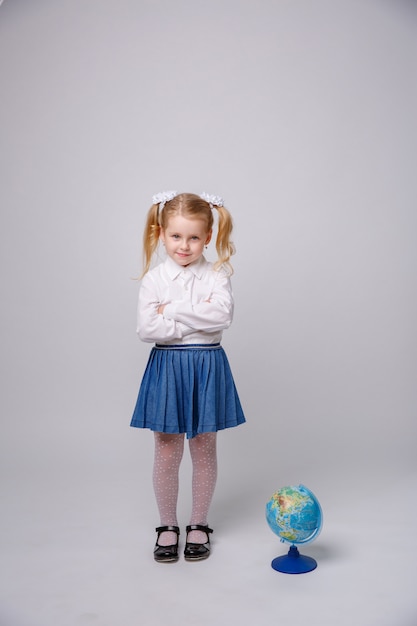 Weinig studentenmeisje met bol van de wereld op witte achtergrond