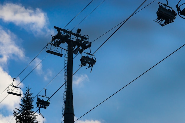 Weinig vier zetels skisnowboardlift bij skitoevlucht met groepen mensen en mooie blauwe hemel