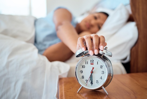 Wekker slaapkamer en vrouw stoppen de tijd om wakker te worden van de vroege ochtend slapen thuis huis en appartement Moe vrouwelijke snooze horloge timer geluidswaarschuwing en geluid om wakker te worden om zonsopgangdag te beginnen