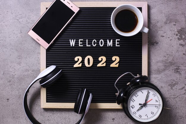 Welcome 2022 creative flat lay composition with office accessories on grey background