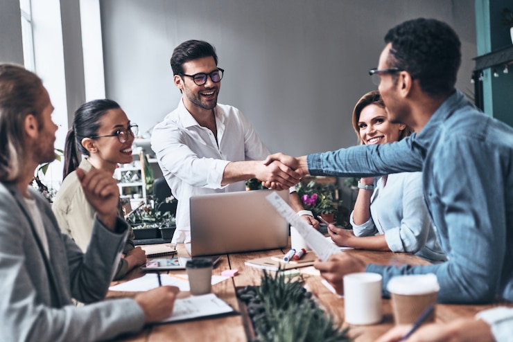 Photo welcome on board! two men in smart casual wear shaking hands and smiling while working in the creative office