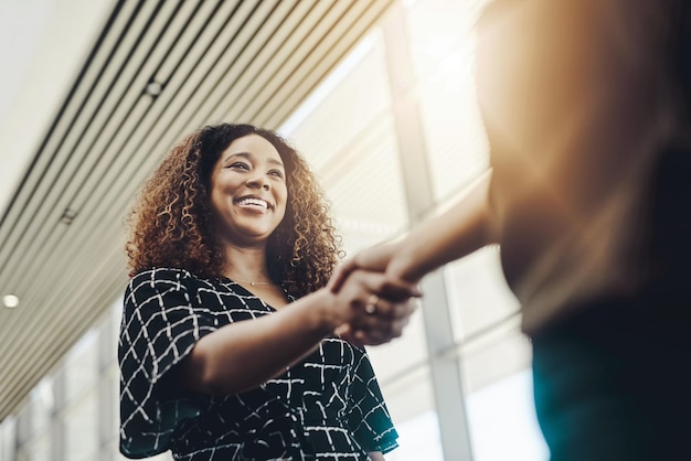 Welcome to the company Low angle shot of an attractive young businesswoman shaking hands with an associate in a modern workplace