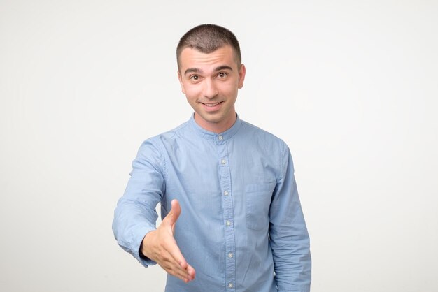 Welcome concept Handsome young hispanic man stretching out hand for shaking