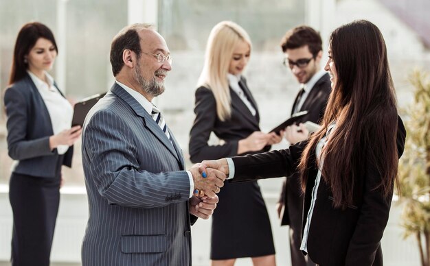 Foto stretta di mano di benvenuto tra avvocato e cliente sullo sfondo del team aziendale