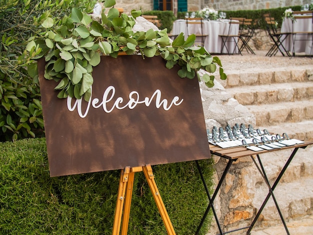 Photo welcome inscription on wooden board in green garden background on wedding ceremony rustic handwritte