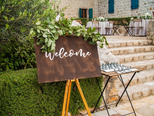 Photo welcome inscription on wooden board in green garden background on wedding ceremony rustic handwritte