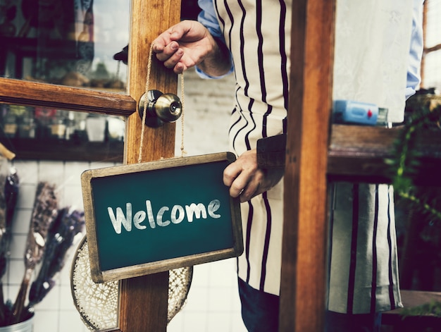 Foto segno di benvenuto appeso a una porta di vetro