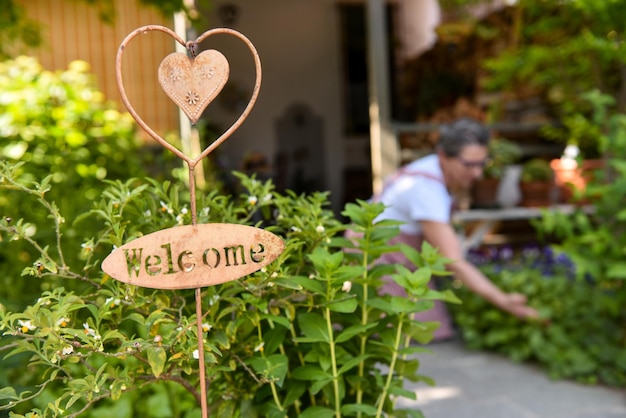 welcome sign in home garden woman working in the background