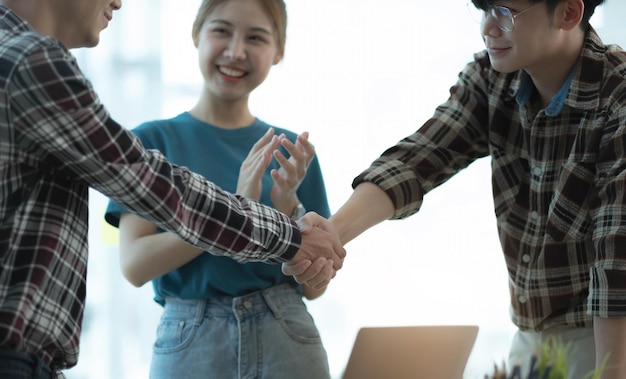 Welcome to the team Men hold men's hands and smile at each other as colleagues clap their hands in a business meeting