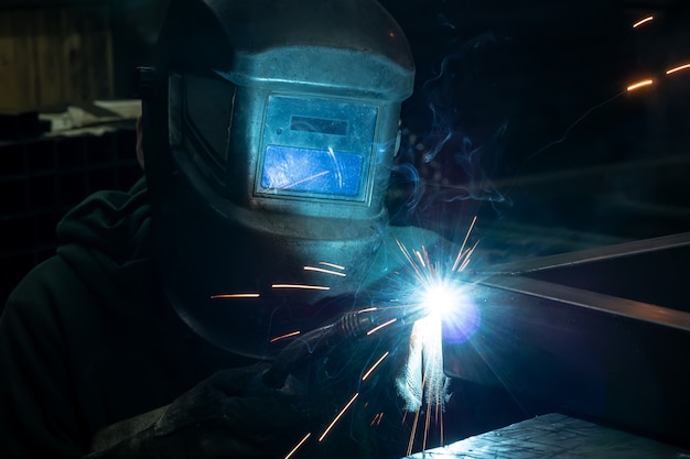 The welder cooks the frame. The welder cooks the metal. The welder cooks metal structures. Welding works. Sparks, molten metal