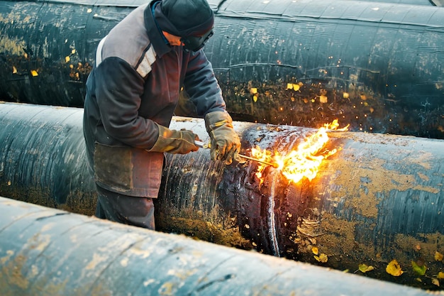 The welder cuts large metal pipes with ocetylene welding