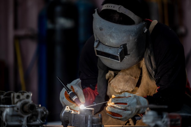 Welder in face mask welds with argon arc stainless steel welding Industrial worker at the factory