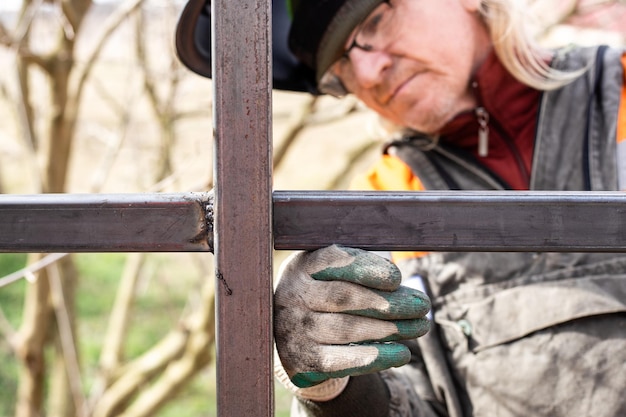 welder tries on a profile pipe on a metal structure for welding with an electric welding machine