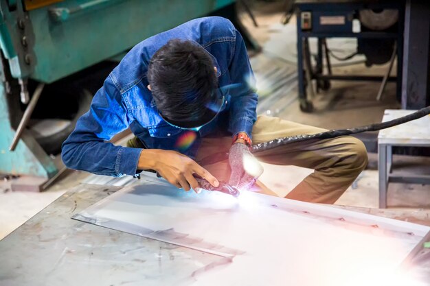 Welder used grinding stone on steel in factory with sparks, Welding process at the industrial workshop, hands with instrument in frame.