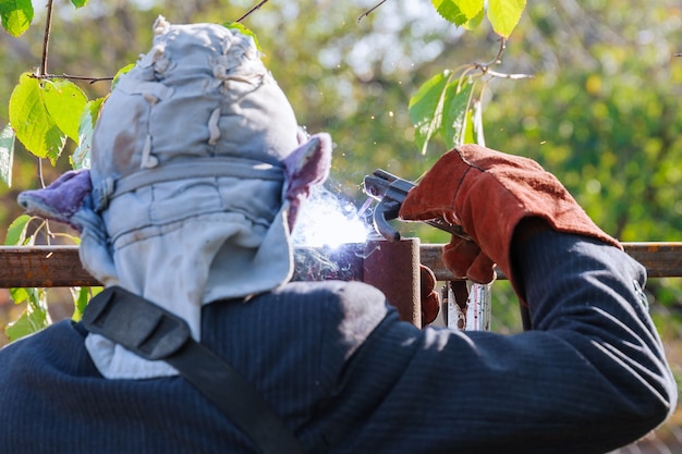 Welder welding a fence in the street. electric welder makes the
fence in manor.