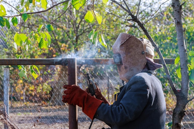 Welder welding a fence in the street. electric welder makes the
fence in manor.