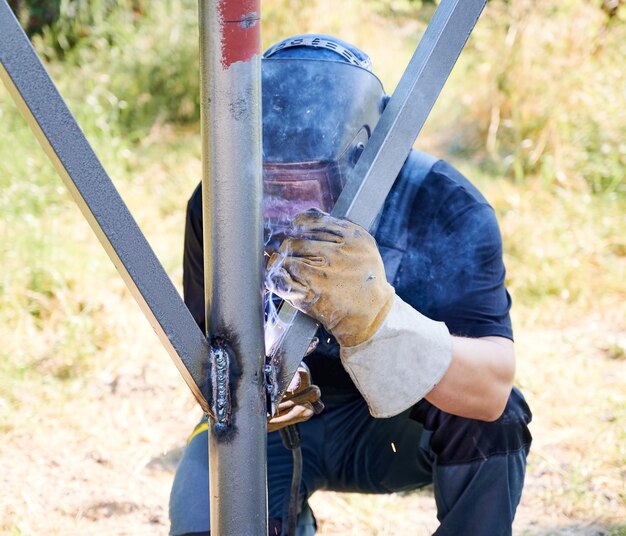 welder welding metal beam with welding machine
