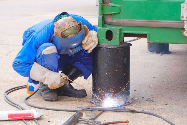 Welder welding metal bollards to use for support foundation of the old steel office container