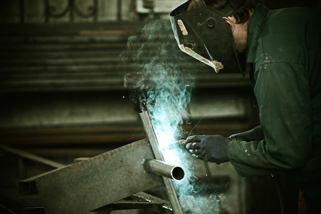 Welder with protective mask welding metal and sparks