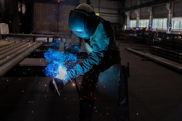 Photo the welder works in the workshop the moment of welding of metal structures beautiful sparks during