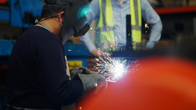 Welders welding steel in factory welders with protective mask