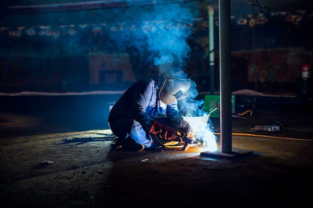 Welding male worker metal is part in machinery tank plate bottom construction petroleum oil and gas storage tank inside confined spaces.