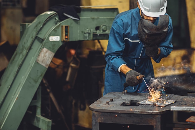 Foto team di saldatori che lavorano saldatura ad arco produzione di giunti metallici nell'industria pesante pericolo e rischio sul posto di lavoro con dispositivi di sicurezza per gli occhi