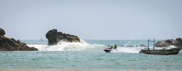 Weligama Sri Lanka 10 29 2022 Jet ski rider fishing boat and the sea rocks on the beach young male enjoying the vacation on the tropical beach