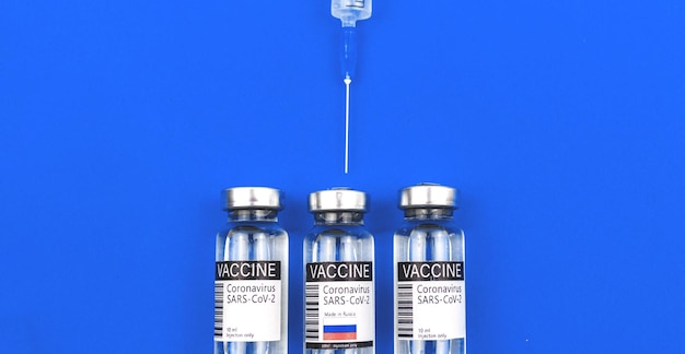 Welk vaccin om conceptbanner te kiezen, concept van vaccinflesjes in de VS, het VK en Rusland, vaccinatie in de wereld, blauwe achtergrondfoto?