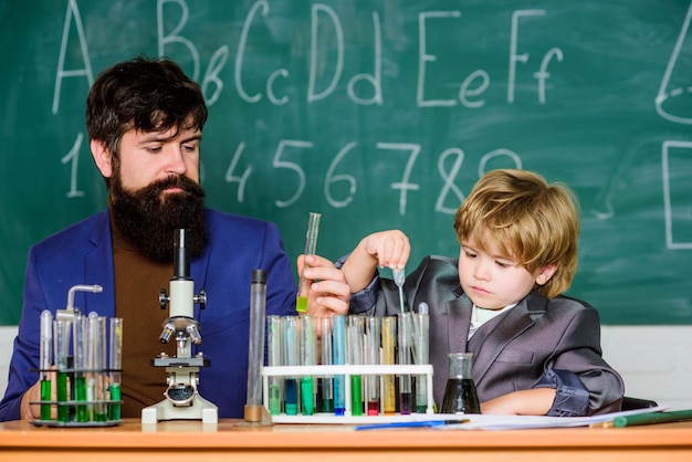 Welkom terug naar school leerling jongen in de scheikunde klas bebaarde man leraar met kleine jongen vader en zoon op school vertrouwen charisma Terug naar school Science chemistry concept