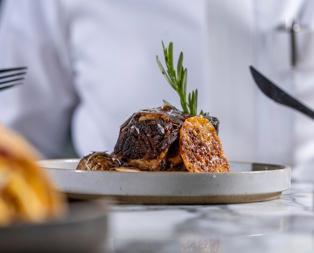 A well cooked piece of meat in a restaurant with white background.