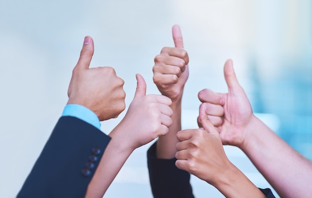 Well done Shot of a group of office workers showing thumbs up together