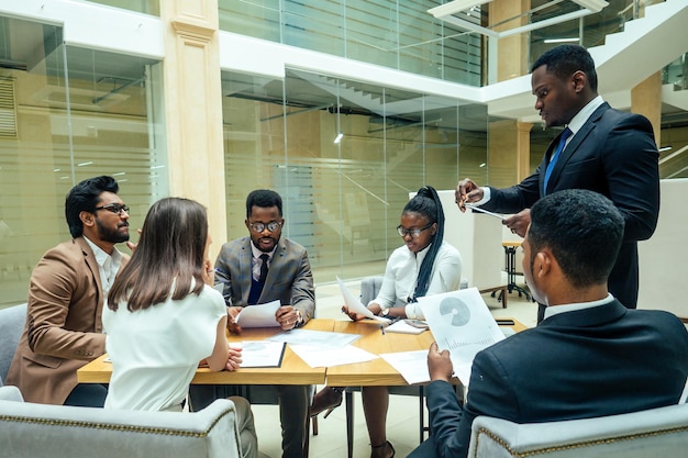 현대 사무실에서 부하 직원에게 보고하는 잘 차려입은 비즈니스 아프리카계 미국인 남성