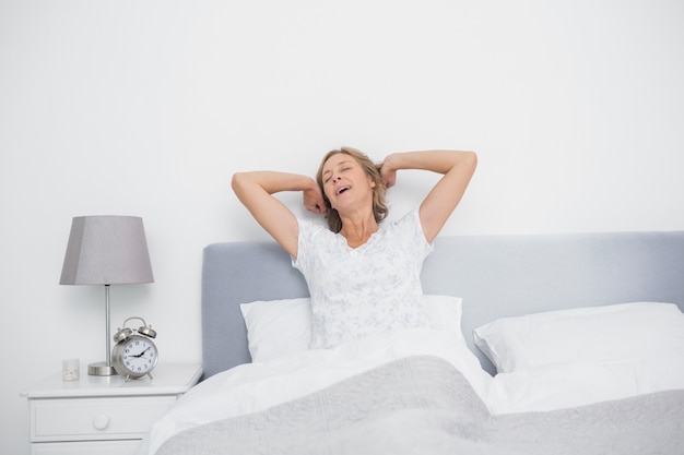 Well rested blonde woman stretching and yawning in bed