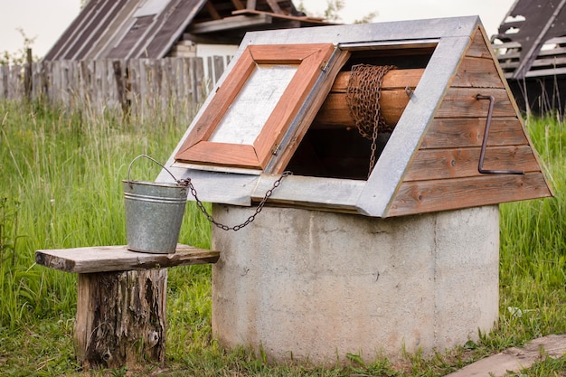 Well in the Russian village with a bucket exposed on the bench