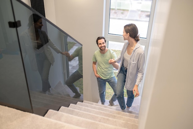 Foto benessere. vista dall'alto della donna che tiene la mano dell'uomo sorridente che si guarda mentre sale le scale a casa