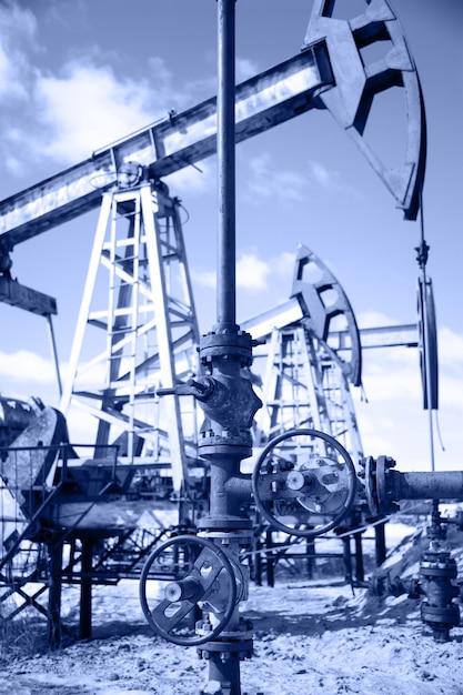 Photo wellhead with valve armature and pump jack. extraction of oil. toned.