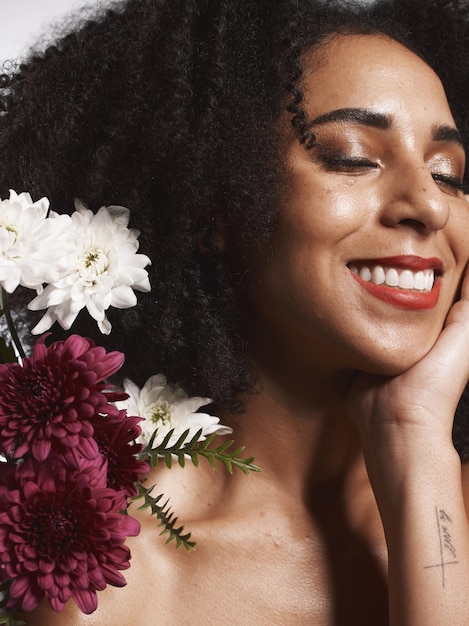 Foto fiori del benessere e modello estetico di bellezza con soddisfazione per la cura della pelle e routine di consistenza luminosa salute estetica e trucco del modello di cosmetici donna nera con bel sorriso in studio bianco