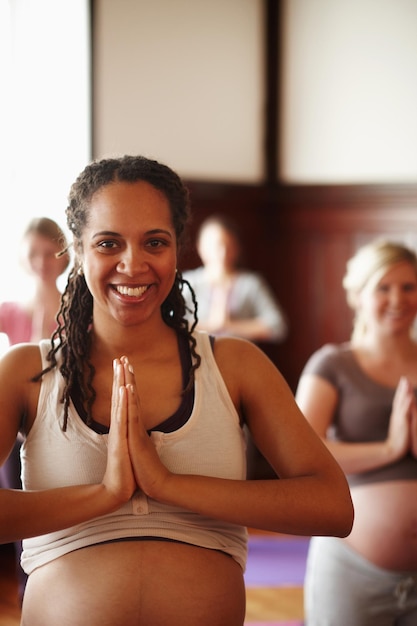 Yoga benessere e meditazione di amiche incinte o donne con salute spirituale e stile di vita sano con il segno delle mani di preghiera ritratto di madre felice di essere in lezione di yoga con il sorriso in uno studio zen