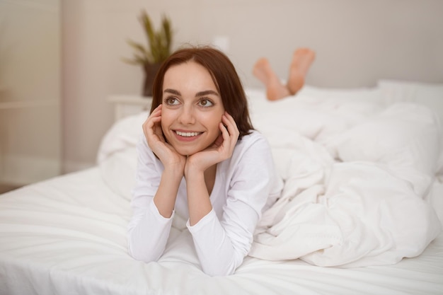 Wellrested young brunette enjoying happy morning posing in bed