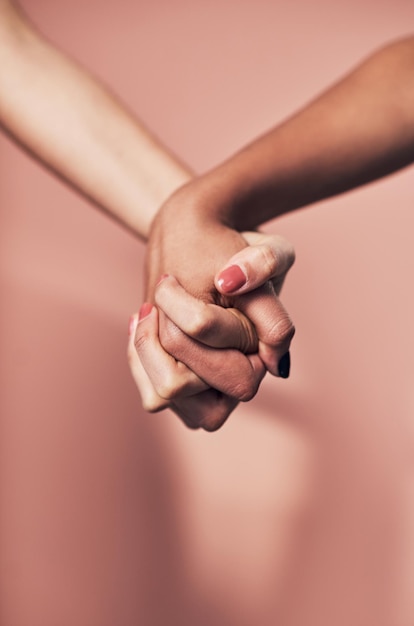 Were capable of so much when we stand together Shot of two unrecognizable women holding hands against a pink background