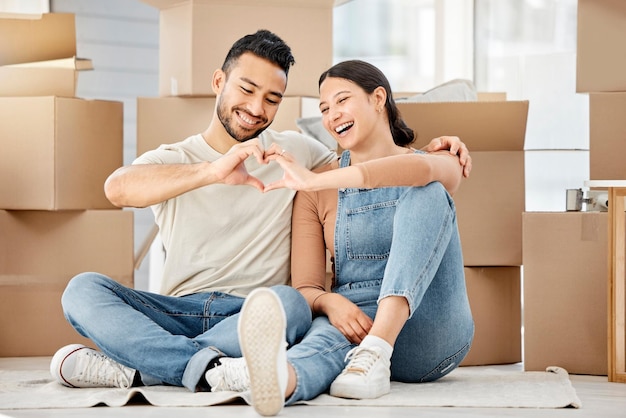 Were going to fill this home with all our love. Shot of a young couple making a heart shape with their hands while moving house.