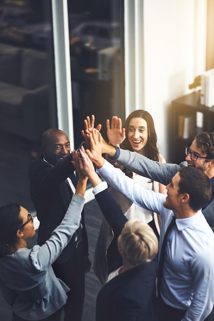 Photo were going to succeed no matter what shot of a group of businesspeople high fiving in an office