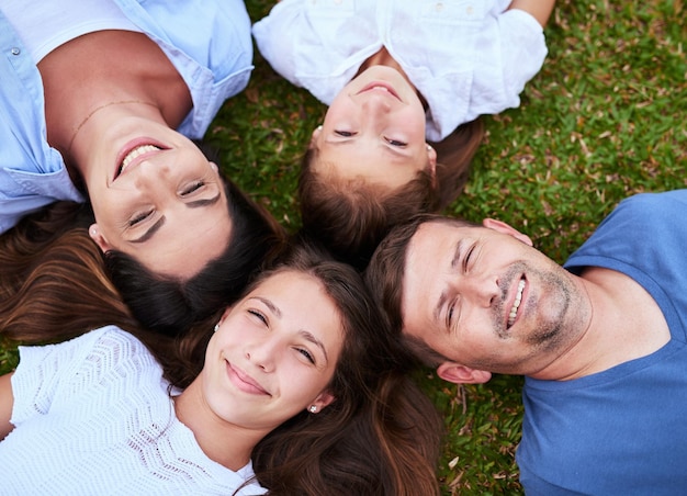 Were just a bunch of peas in a pod Portrait of a cheerful family lying on the ground together outside in a park during the day