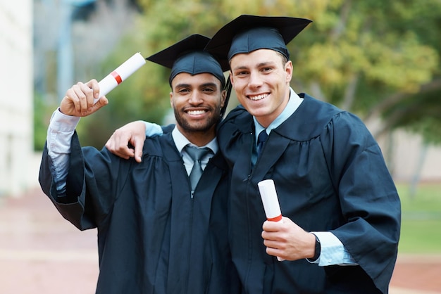 Were on our way to success Two young college graduates holding their diplomas while wearing cap and gown