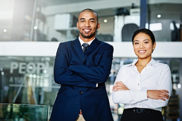 Were the perfect team Portrait of two young businesspeople standing with their arms folded in the office