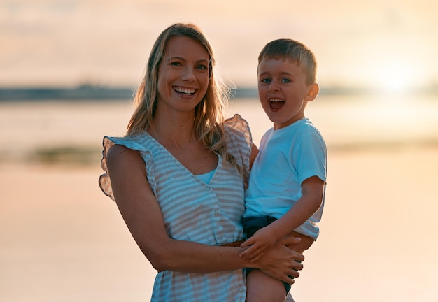 Were watching the sunset Shot of a young mother spending time with her son at the beach