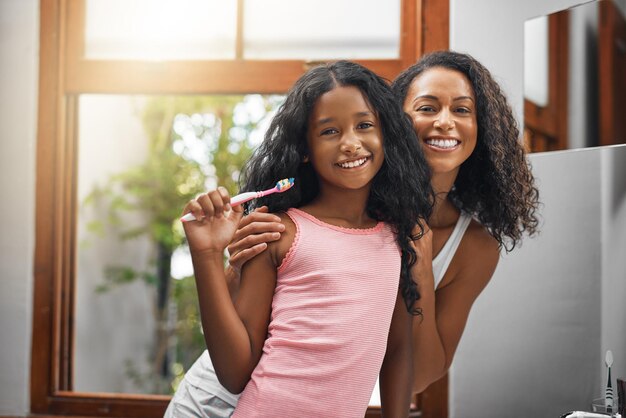 Were wearing matching smiles today Cropped portrait of an attractive young woman and her daughter brushing their teeth in the bathroom at home