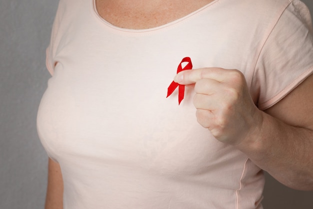 Wereld Aids Dag. Een vrouw met een rood lint op een T-shirt op een zwarte achtergrond.